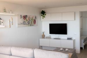 ein Wohnzimmer mit einem weißen Sofa und einem Flachbildfernseher in der Unterkunft Exclusive & Elegant Luxury Stay with Stunning Ocean Views in San Bartolomé de Tirajana