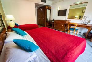 a bedroom with a red and white bed and a desk at Topaz Hotel in St Paul's Bay
