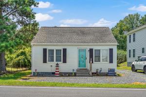 a small white house with a blue door at Lazy Days - Pet friendly with screened gazebo! in Deep Hole