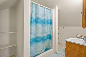 a bathroom with a shower with a blue shower curtain at Lazy Days - Pet friendly with screened gazebo! in Deep Hole +26 photos