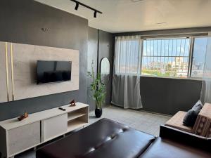 een woonkamer met een bank en een flatscreen-tv bij Vista mar, piscina, na praia do futuro, com Ar condicionado e Wi-Fi in Fortaleza