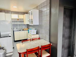 een keuken met een tafel, stoelen en een koelkast bij Vista mar, piscina, na praia do futuro, com Ar condicionado e Wi-Fi in Fortaleza