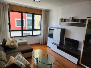 a living room with a couch and a tv at CREDENCIAL Avda BECERREA in Sarria