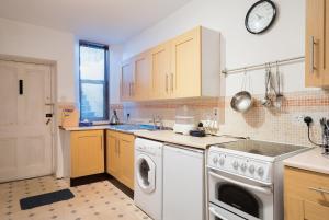 a kitchen with a washing machine and a clock on the wall at Aberdeen City Flat, close to city centre in Aberdeen +5 photos