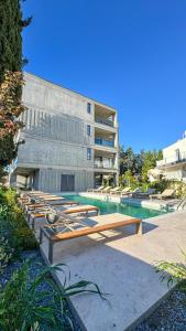 a building with a swimming pool with benches next to it at Malberry Park 202 - Modern 2bedroom Apt with Shared Heated Pool, Sauna, Gym, Jacuzzi in Paphos City