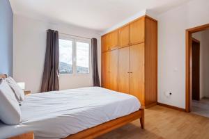 1 dormitorio con 1 cama con armario de madera y ventana en SunRise Vila, en Estreito da Calheta