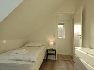 a white bedroom with a bed and a mirror at Cozy house with 2 bedrooms on the sea coast in Assens