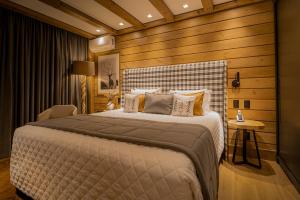a bedroom with a large bed and a wooden wall at Hotel Alpestre in Gramado
