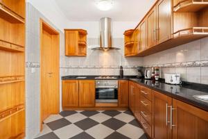 Una cocina con gabinetes de madera y piso a cuadros. en SunRise Vila, en Estreito da Calheta