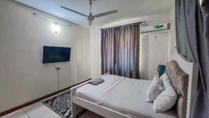 a bedroom with a bed and a tv on the wall at The Rosebay Apartment in Mombasa