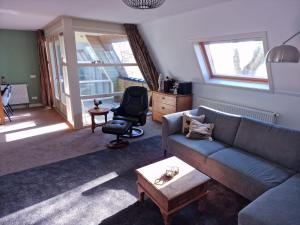a living room with a couch and a chair at Tussen Wad en Dijk - Vakantieappartement in Sint Jacobiparochie
