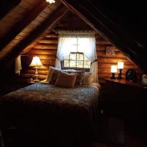 a bedroom with a bed with two lamps and a window at Deer Valley Retreat, Lovely Log Cabin with Fireplace & Garden Views- Perfect for a Relaxing Getaway! in Bradford