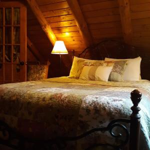 a bedroom with a large bed with a lamp at Deer Valley Retreat, Lovely Log Cabin with Fireplace & Garden Views- Perfect for a Relaxing Getaway! in Bradford