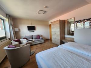 a bedroom with a bed and a couch and a tv at Pension Heuer in Brietlingen