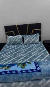 a bed with a blue comforter and two pillows at شقق مفروشة الحكمة in Laayoune