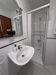 a white bathroom with a sink and a shower at el valle hostal restaurante in La Pradera de Navalhorno