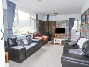 a living room with two leather couches and a television at Callart View in Ballachulish