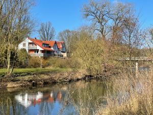 a house with a red roof next to a river at Ferienwohnung Diemelblick in Trendelburg