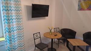 a small table with chairs and a television on a wall at Apartamenty Centrum z wanną dwuosobową in Piotrków Trybunalski