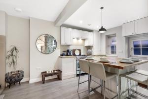 a kitchen with white cabinets and a table and chairs at Magpie Cottage - North East Escapes in Stanhope