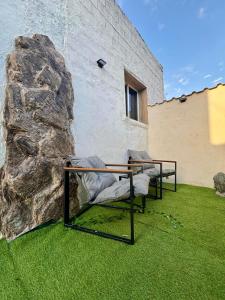 two chairs sitting on grass next to a stone wall at Casita con vistas a la montaña cerca de Murcia in Algezares