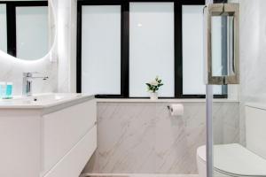 a bathroom with a sink and a toilet and windows at Spacious Modern Home near Airport and Manukau City in Auckland +30 photos