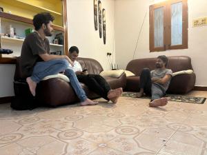 three men sitting on a couch in a living room at Hostel Madras in Chennai