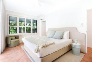 a white bedroom with a large bed and a window at Casa Del Sol Palm Cove in Palm Cove