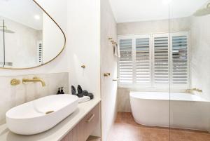 a bathroom with a white tub and a sink and a mirror at Casa Del Sol Palm Cove in Palm Cove +19 photos
