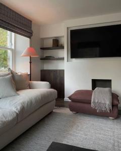 een woonkamer met een bank en een flatscreen-tv bij Old school - Charming Historic Cottage for Seven in Ballater