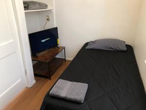 a bedroom with a bed and a flat screen tv at Private house with 3 bedrooms and 1 bathroom and free parking convenient to NYC Manhattan bus and train in Perth Amboy