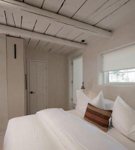 ein weißes Bett mit weißen Kissen und einem Fenster in der Unterkunft Palace Modern Residences at the Railyard - Studio in Santa Fe + 5 Fotos