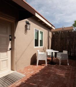 eine Terrasse mit einem Tisch und 2 weißen Stühlen in der Unterkunft Palace Modern Residences at the Railyard - Studio in Santa Fe