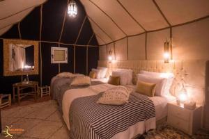 a bedroom with two beds in a tent at Noumidia Luxury Camp in Merzouga