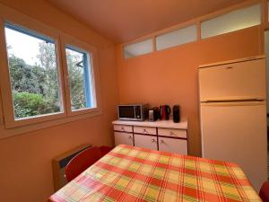 een keuken met een tafel, een koelkast en een raam bij Casa Nunziada in Patrimonio Garden level, Quiet and Bright in Patrimonio