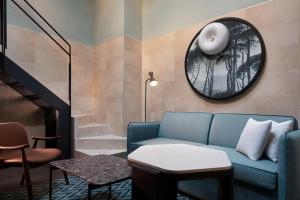 罗马The Spring House Hotel Rome Vatican, Tapestry Collection Hilton的客厅配有蓝色的沙发和圆镜子