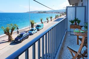 a balcony with cars parked on a street next to the ocean at Sykea Luxury Apartment in Xylokastro