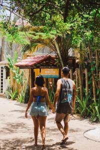 a man and a woman walking down a street at Pousada Beira Mar in Caraíva