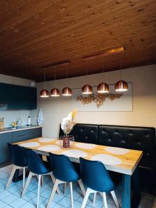 a kitchen with a large wooden table and blue chairs at Le havre du lac in Vielsalm