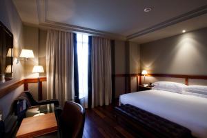 a hotel room with a bed and a desk and a table at Hotel 1898 in Barcelona