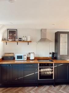 une cuisine avec un comptoir avec un micro-ondes et une cuisinière dans l'établissement The Potting Shed, à Chepstow