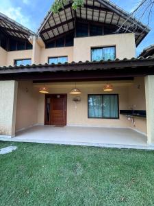 a house with a door and a grass yard at Residencial Ravena Arraial d'ajuda Casa 7 in Arraial d'Ajuda