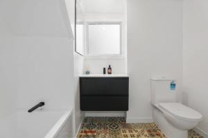 a bathroom with a toilet and a sink and a window at Papawai Townhouse 11 in Rotorua +6 photos
