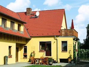 a yellow house with a red roof and a table at Ferienwohnung, Beetzseeheide in Ketzür