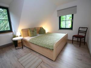 a bedroom with a bed and a chair and two windows at Doppelhaushälfte, Glave in Glave