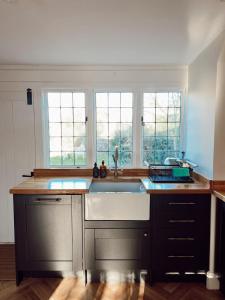 une cuisine avec un évier et deux fenêtres dans l'établissement The Potting Shed, à Chepstow