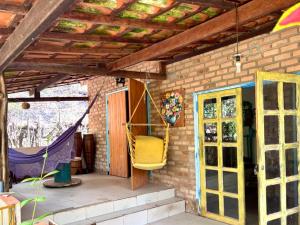 a porch with a yellow chair hanging from a brick wall at Vila Alamandra in Ibicoara