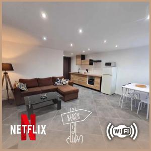 ein Wohnzimmer mit Sofa und eine Küche in der Unterkunft Les Voiles Blanches, T3 neuf de 53 m2 in Saint-Jean-de-Monts