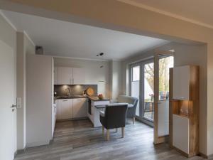 a kitchen with white cabinets and a table and a chair at Exclusives Appartement auf Fehmarn in Petersdorf auf Fehmarn