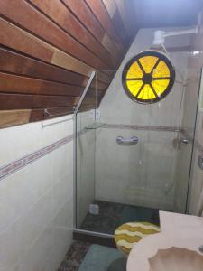a bathroom with a glass shower with a clock on the wall at Chalé Schueler in Nova Friburgo +47 photos